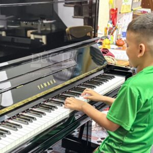 Khách hàng nhí đang trải nghiệm chiếc đàn piano Yamaha U1A tại Showroom của Piano Đức Trí