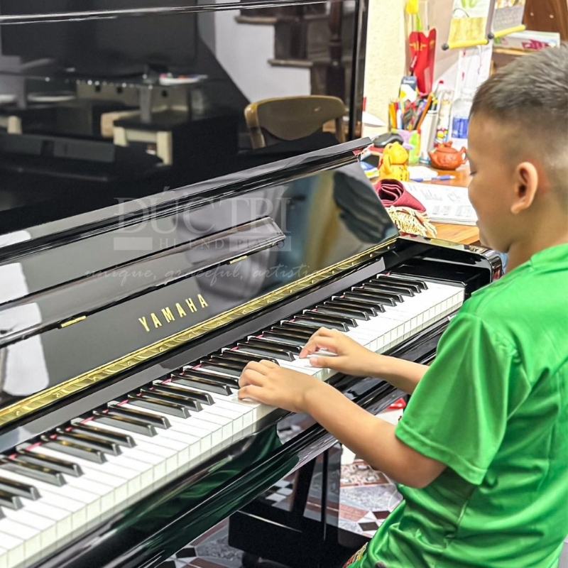 Khách hàng nhí đang trải nghiệm chiếc đàn piano Yamaha U1A tại Showroom của Piano Đức Trí