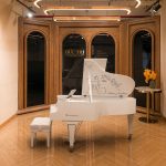 Đàn grand piano bosendorfer cocteau trắng trong phòng trưng bày vòm gỗ có hoa vàng