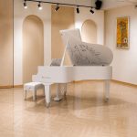 Đàn piano bosendorfer cocteau màu trắng trong phòng trưng bày vòm sáng có ghế và tranh