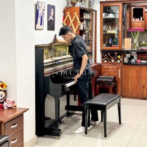 Nhân viên kĩ thuật của Piano Đức Trí đang điều chỉnh dây đàn piano Yamaha YUS5 cho khách hàng