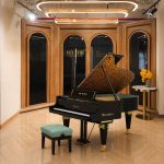Đàn grand piano Bösendorfer Secession và ghế xanh trong sảnh vòm gỗ